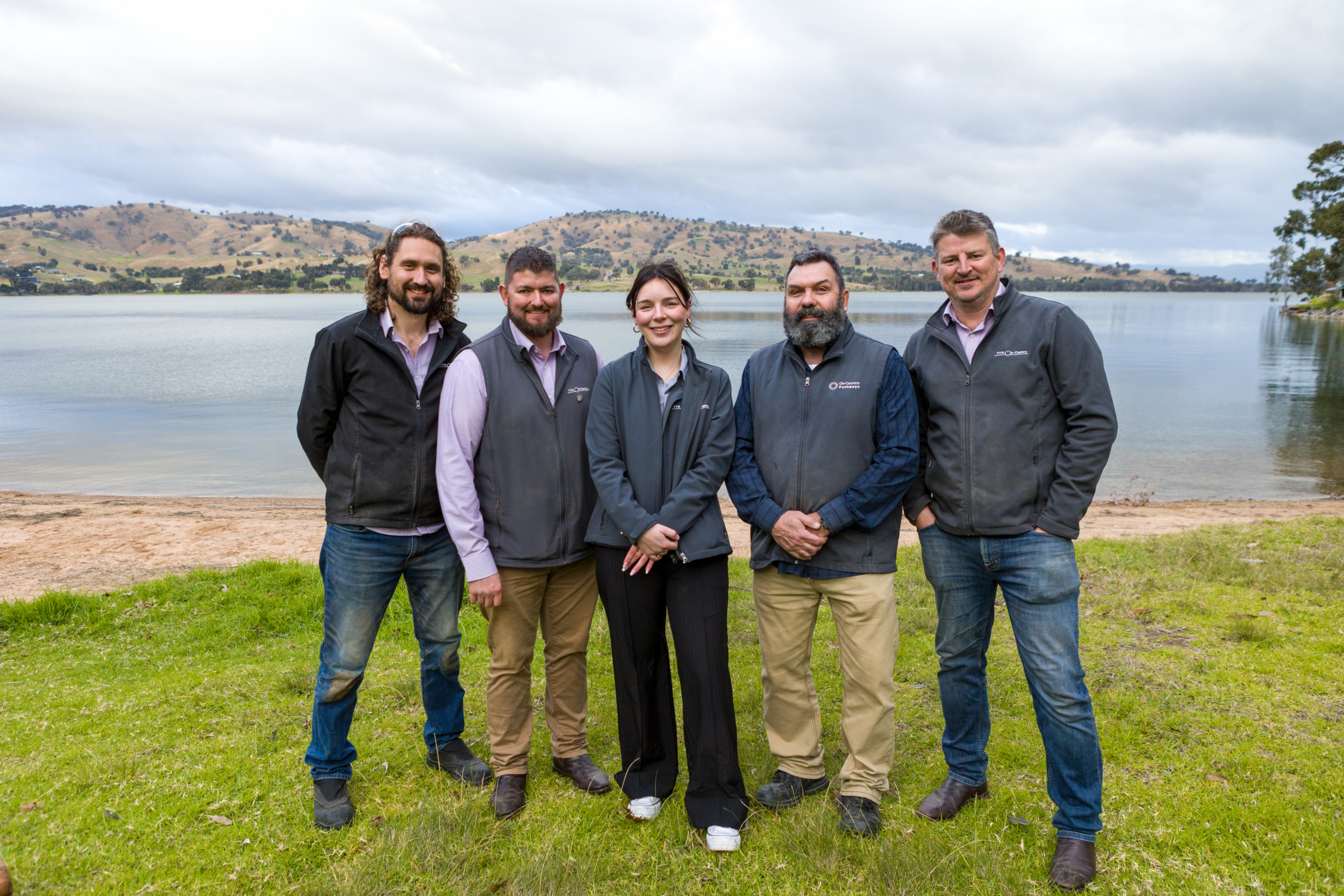 A group of people stand by a lake