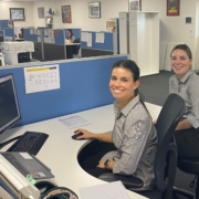 Two young women work at a desk in an office