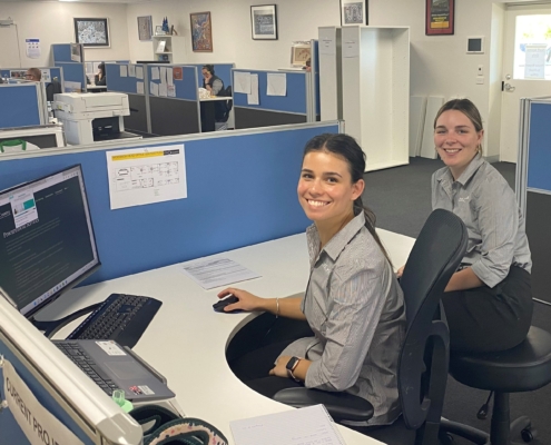 Two young women work at a desk in an office